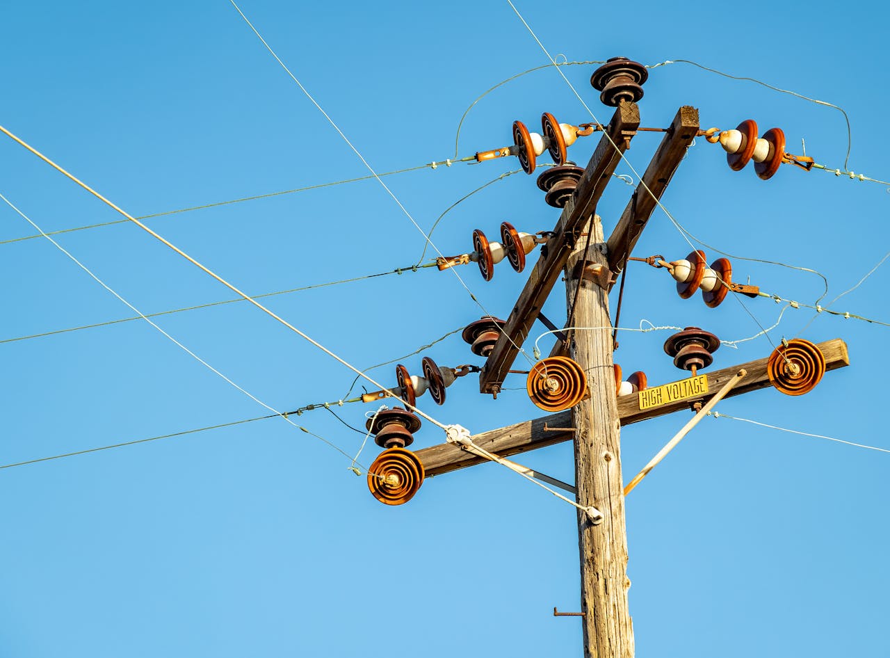 services-10 High voltage power line and insulators captured against a clear blue sky.